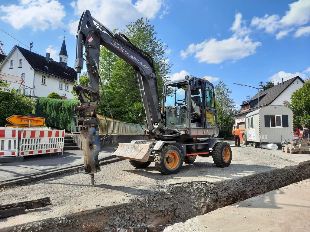 Straßensanierung mit Mobilbagger im kommunalen Tiefbau Mobilbagger mit Hydraulikhammer bei Straßenaufbruch im innerörtlichen Straßenbau