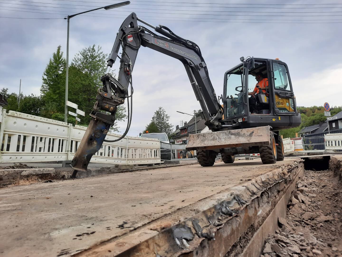 Mobilbagger mit Hydraulikhammer beim Straßenaufbruch im innerstädtischen Straßenbau