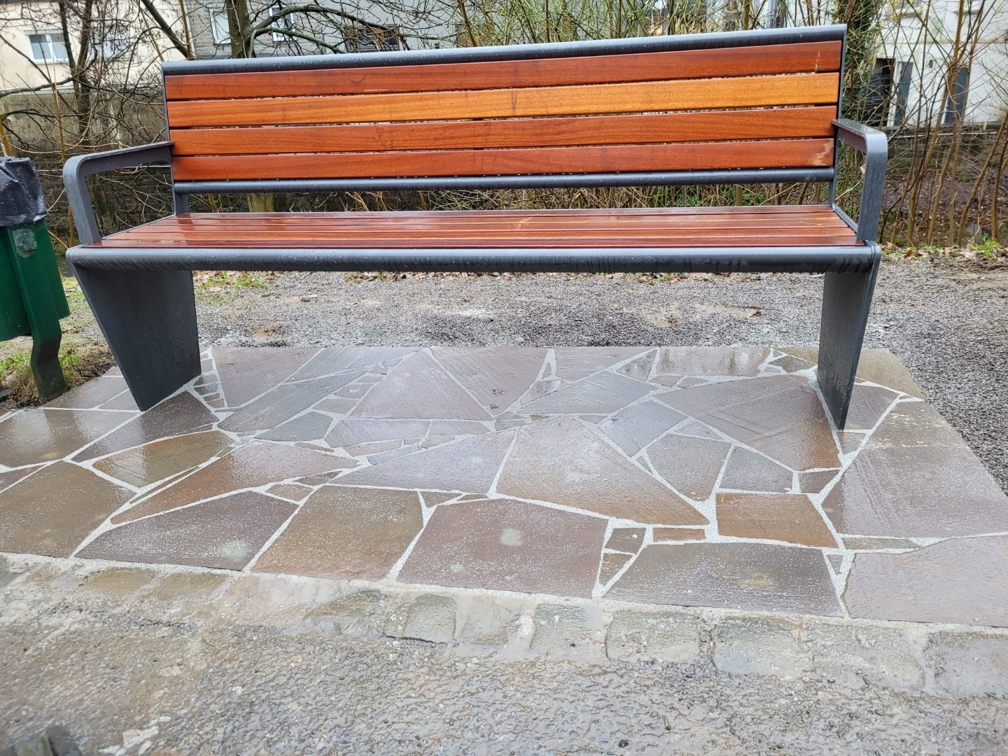 Natursteinpflaster mit Sitzbank im Garten- und Landschaftsbau Sitzbank auf gepflasterter Natursteinfläche im öffentlichen Außenbereich